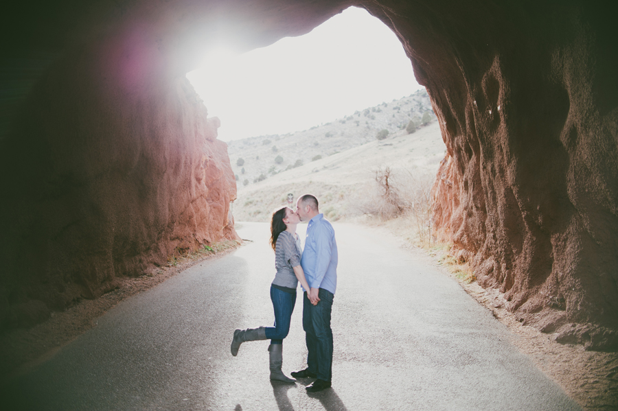 couple kisses in red rocks tunnel for engagement photographer dan hand
