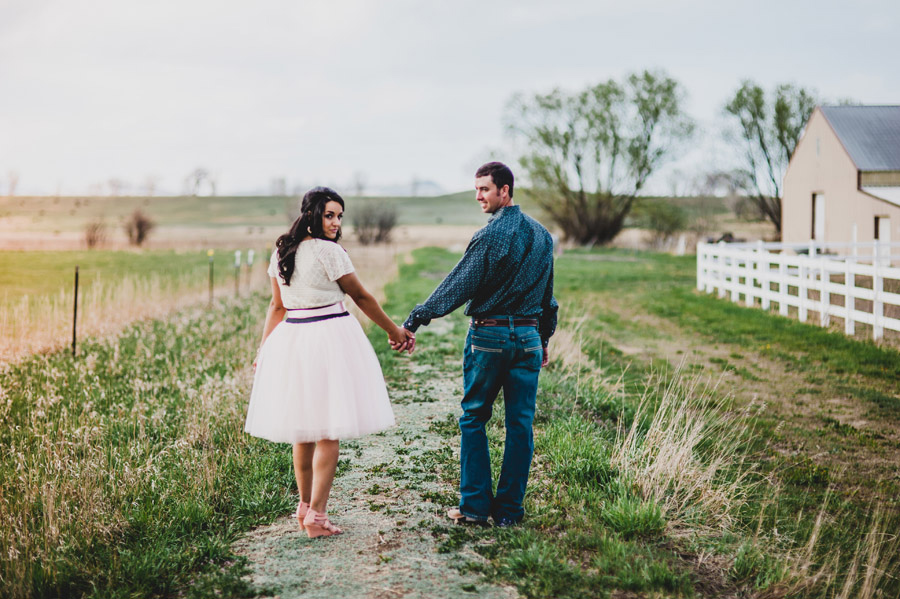 Engaged couple walk along path on Longmont Farm in Colorado