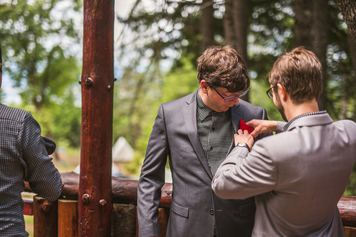 groom helping his groomsman with pocket square